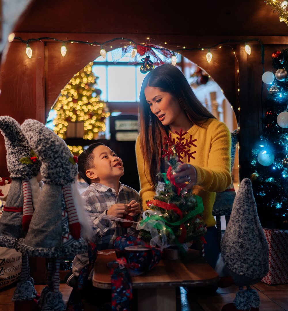 A mom and son look at each other in a giant gingerbread house at Christmas in Banff at the Rimrock Resort.